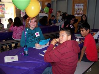 students at a table with balloons  smiling